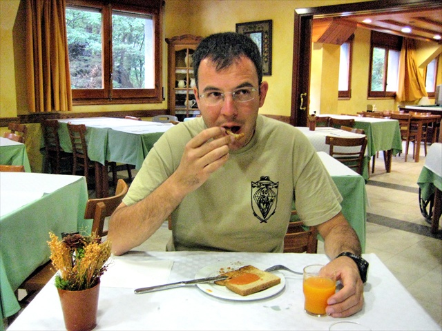 a man eating at a table with sandwiches, juice and fruit