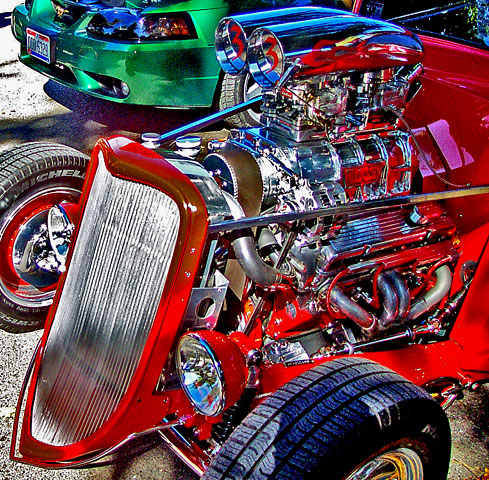 a car with a modified engine sits parked next to another classic car