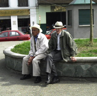 a pair of elderly gentlemen sitting on the side of the road