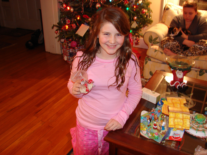 a little girl standing by christmas presents on a coffee table