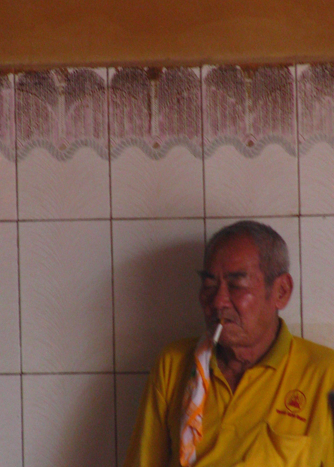 a man wearing a yellow shirt brushing his teeth