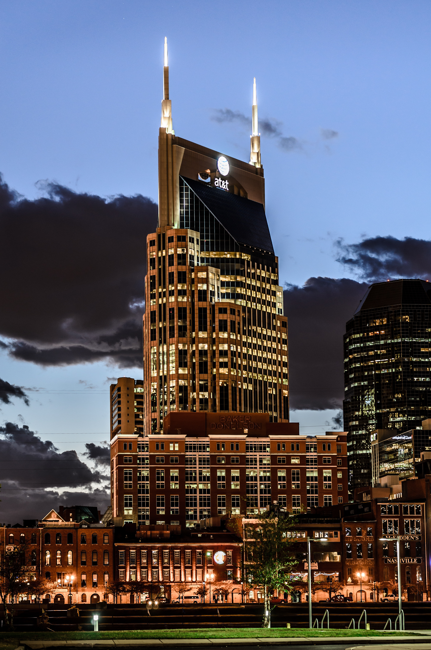 a skyscr is lit up at dusk with clouds