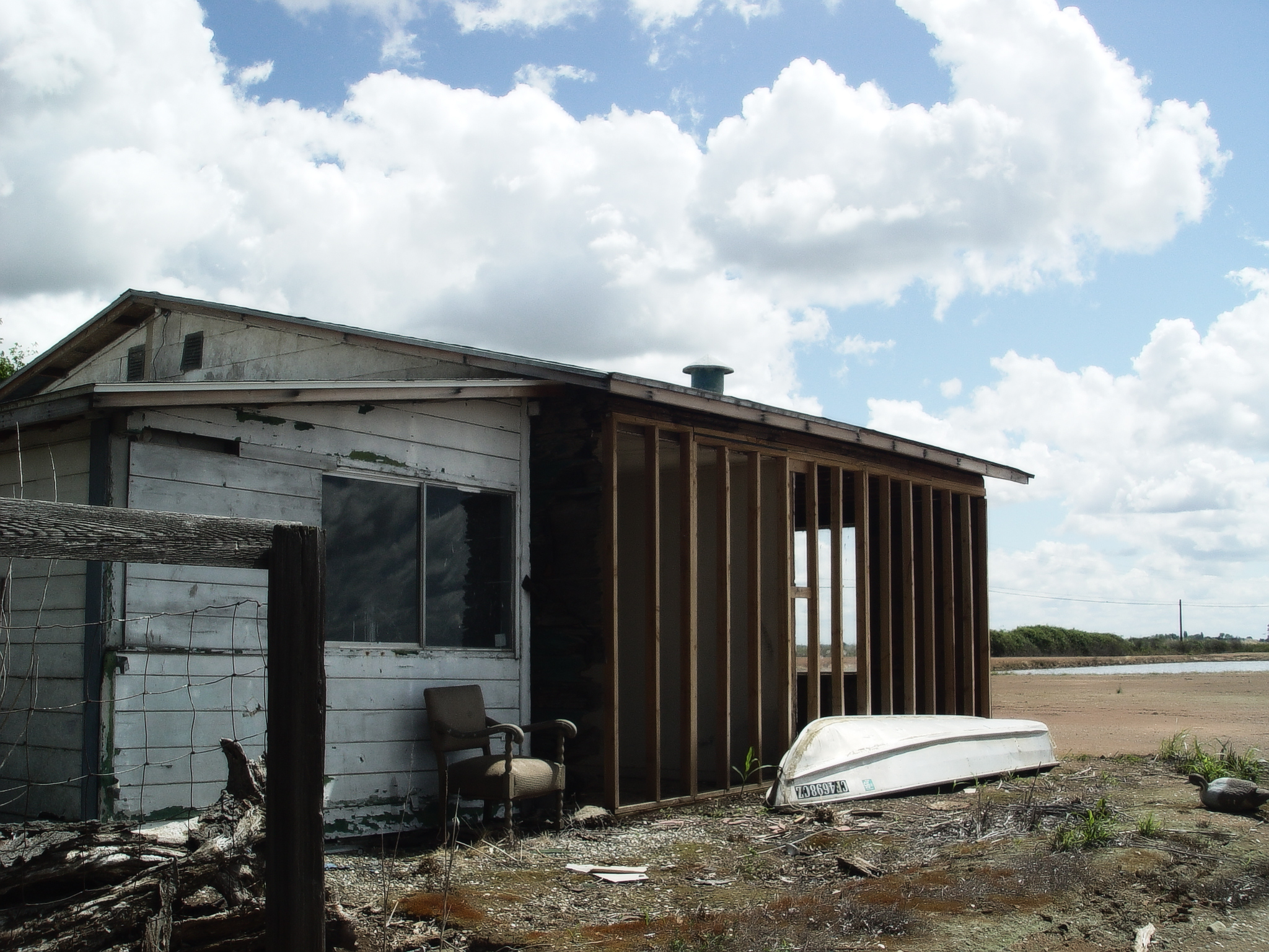 an abandoned wooden shed with a white boat outside