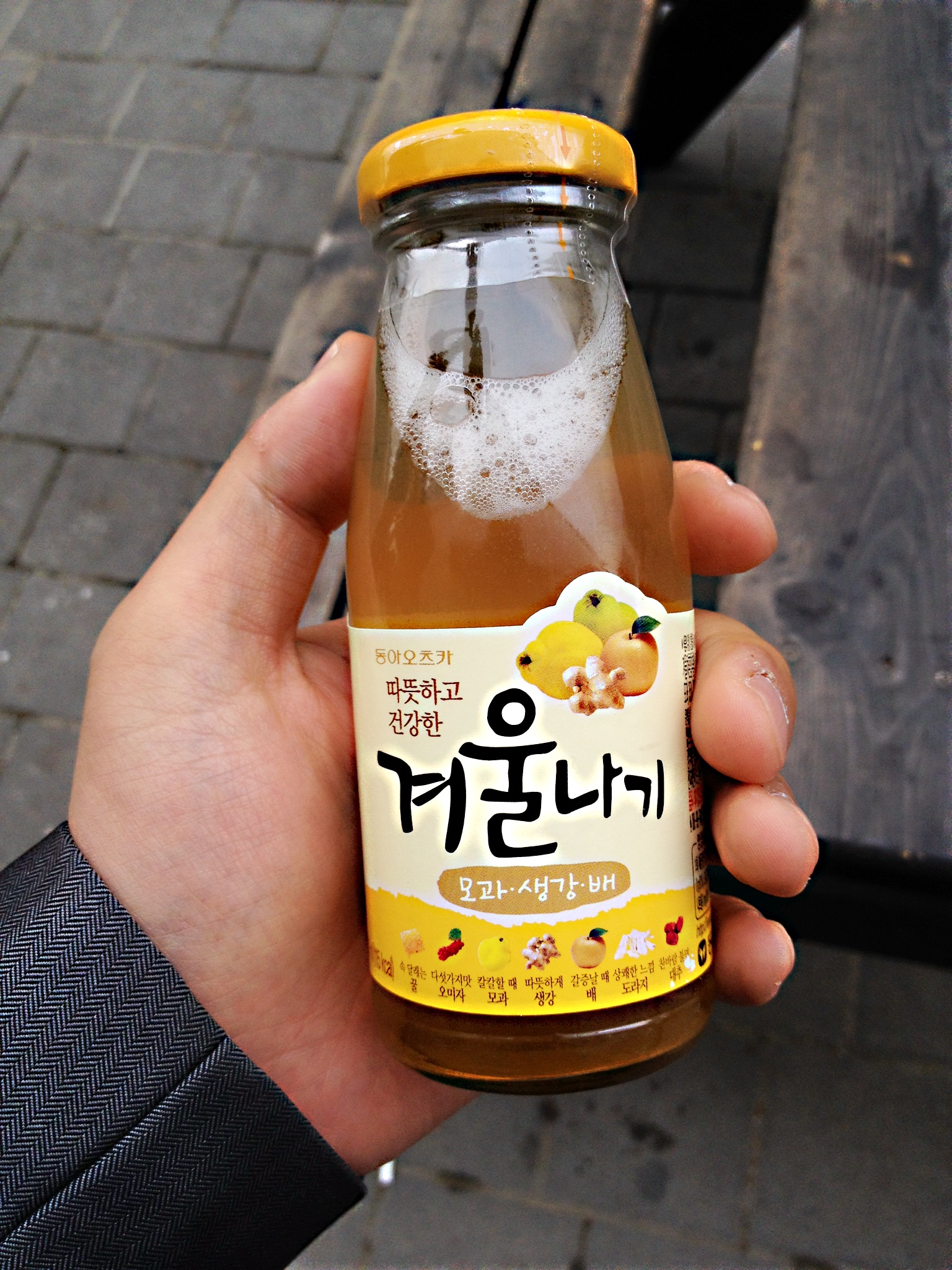 a hand holding a jar of honey with korean writing