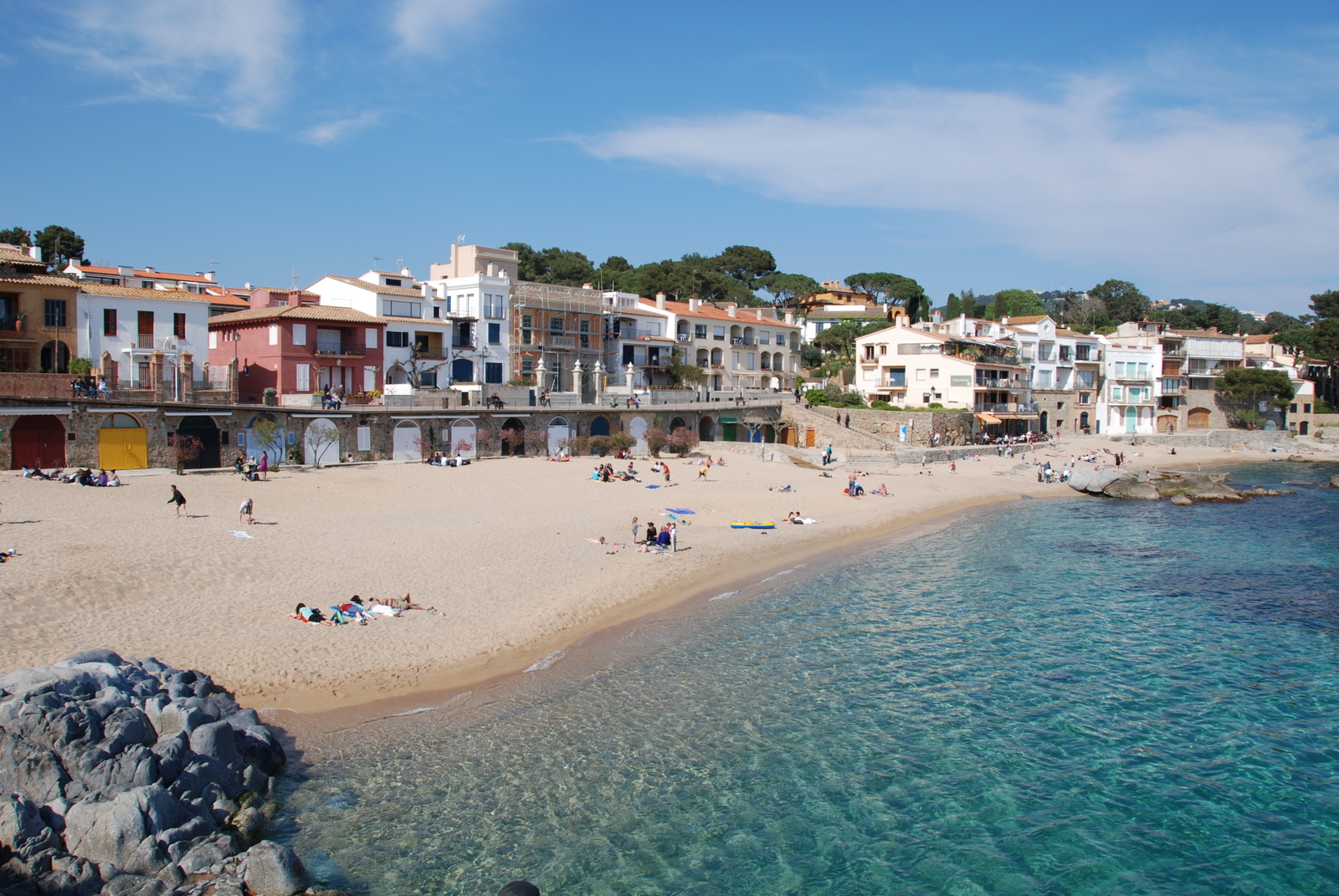 people enjoying the beach and building on both sides of the water