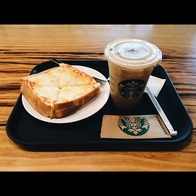 coffee and toast in a take - out tray with the starbucks drink