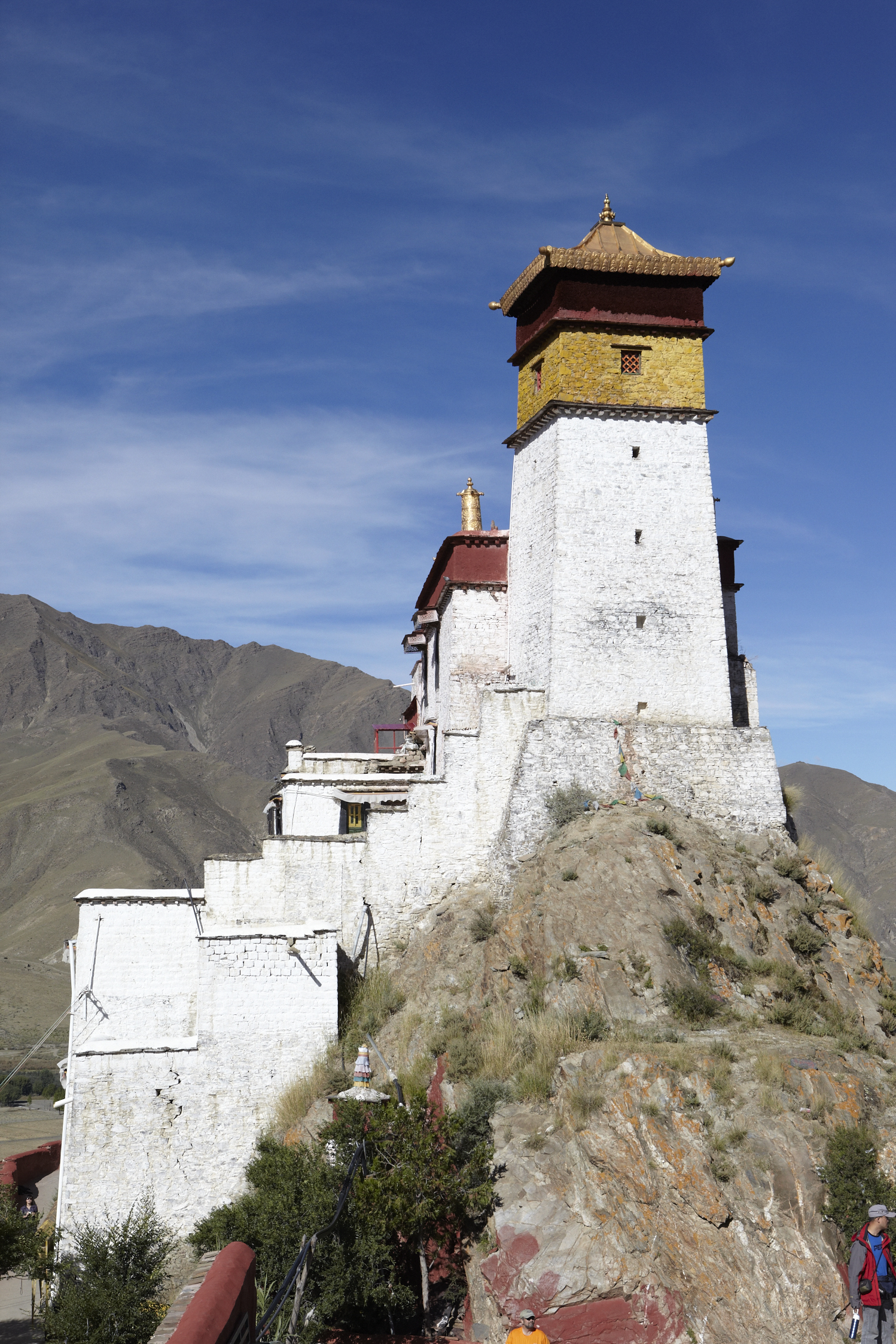 a yellow and white tower on top of a rocky mountain