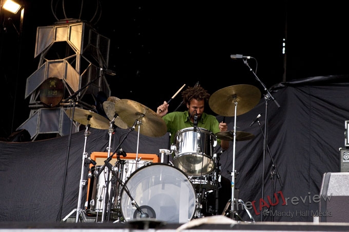 man in green shirt playing on drums at stage