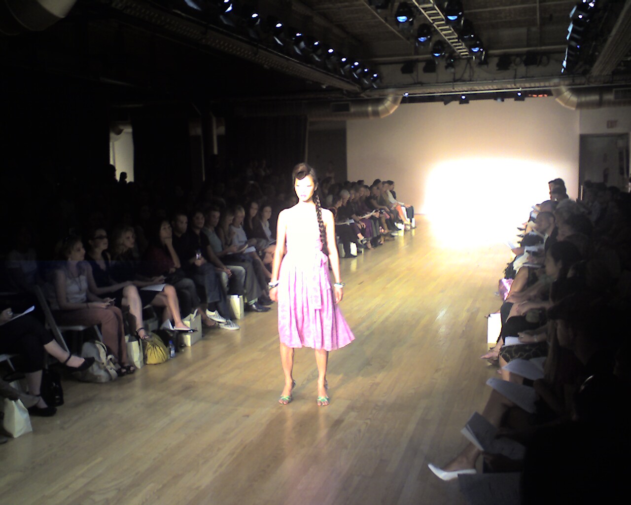 a runway with a woman in a pink dress on the runway
