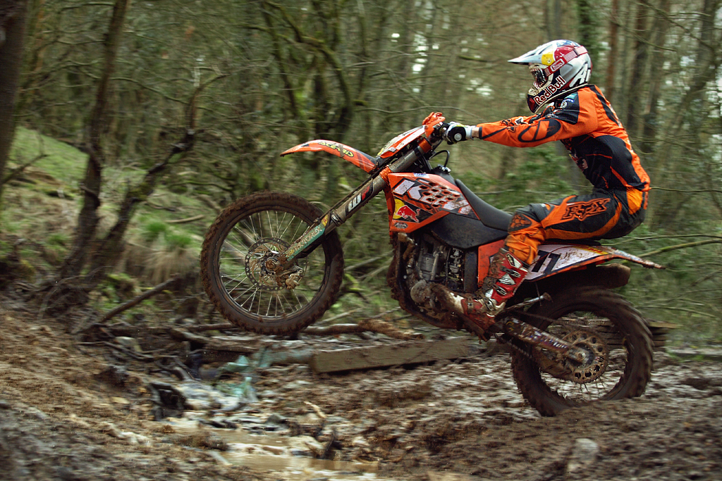 a man riding a dirt bike over a wooden bridge