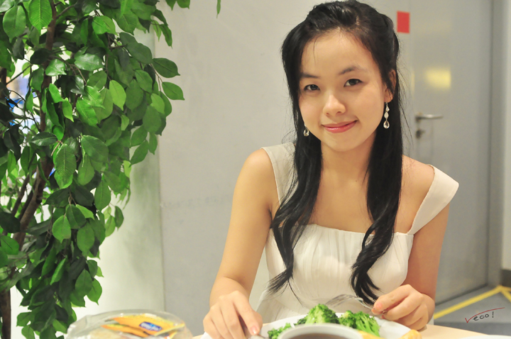 a woman in white is holding a plate with broccoli