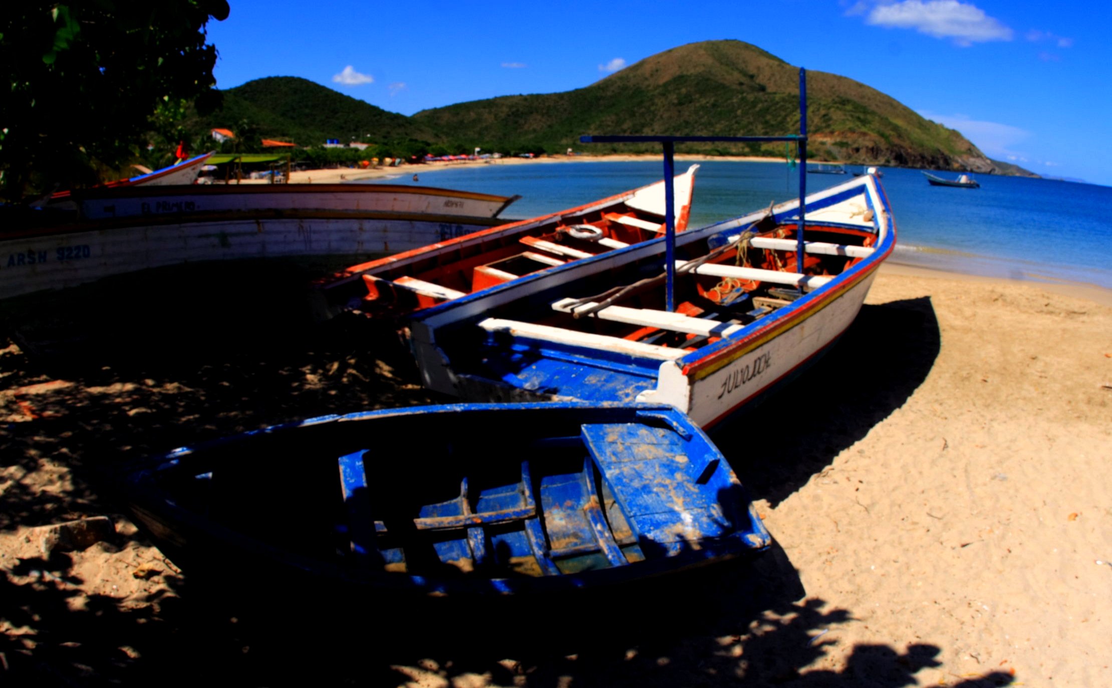 two rowboats sitting on the beach next to water