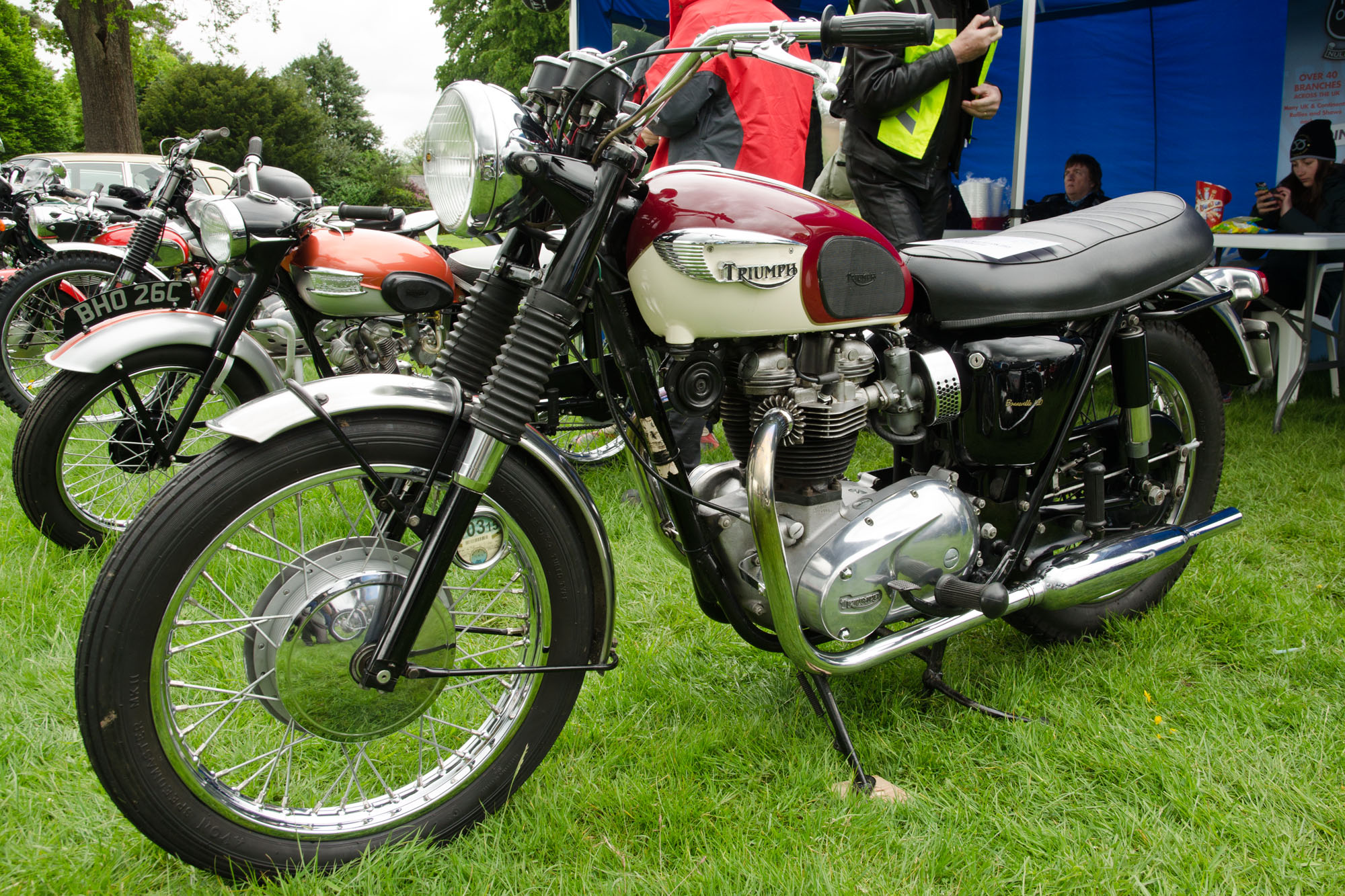 an older model motorcycle at a show, in front of a tent