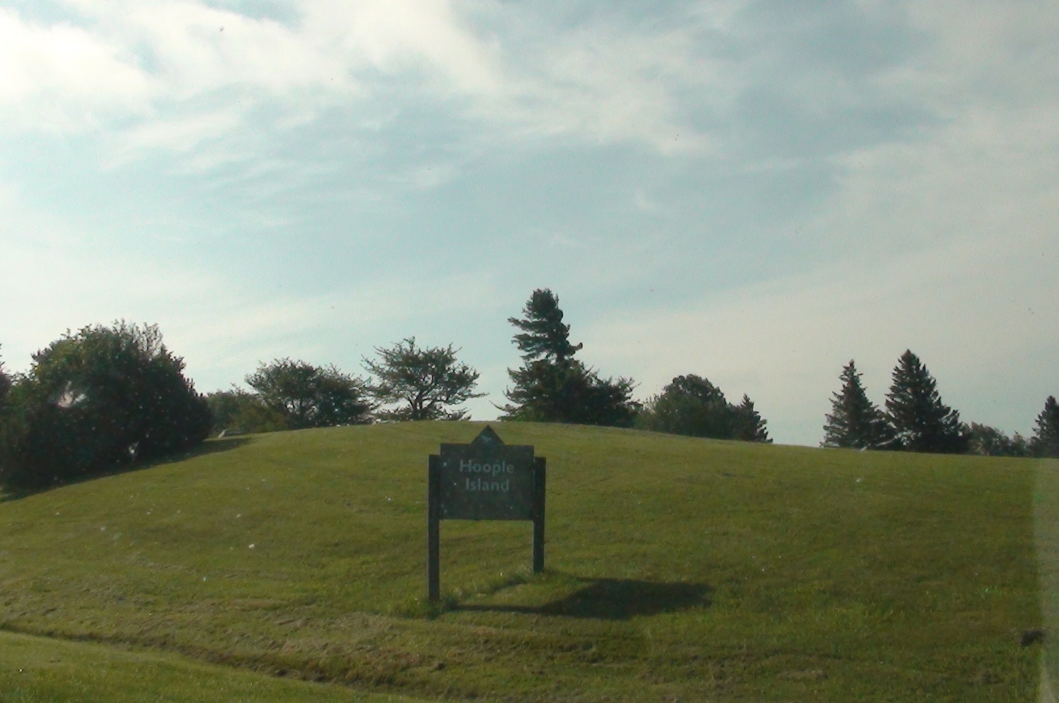 a sign sits on a hill in a grassy area