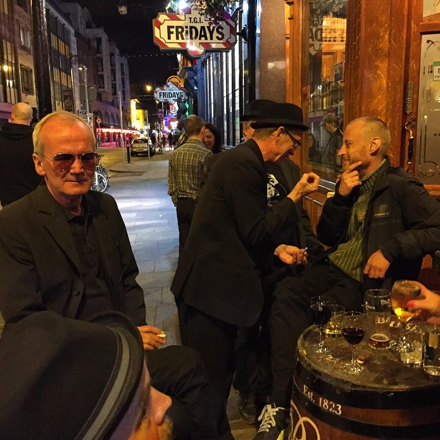 three men sitting at a table drinking outside