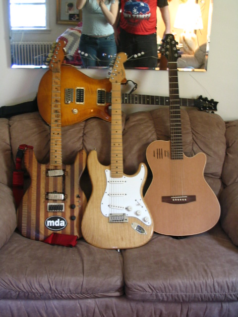 several guitars and electric guitars are piled on top of each other