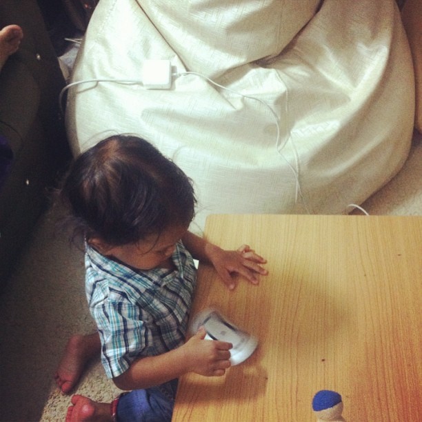 a small child sitting on the floor holding a remote