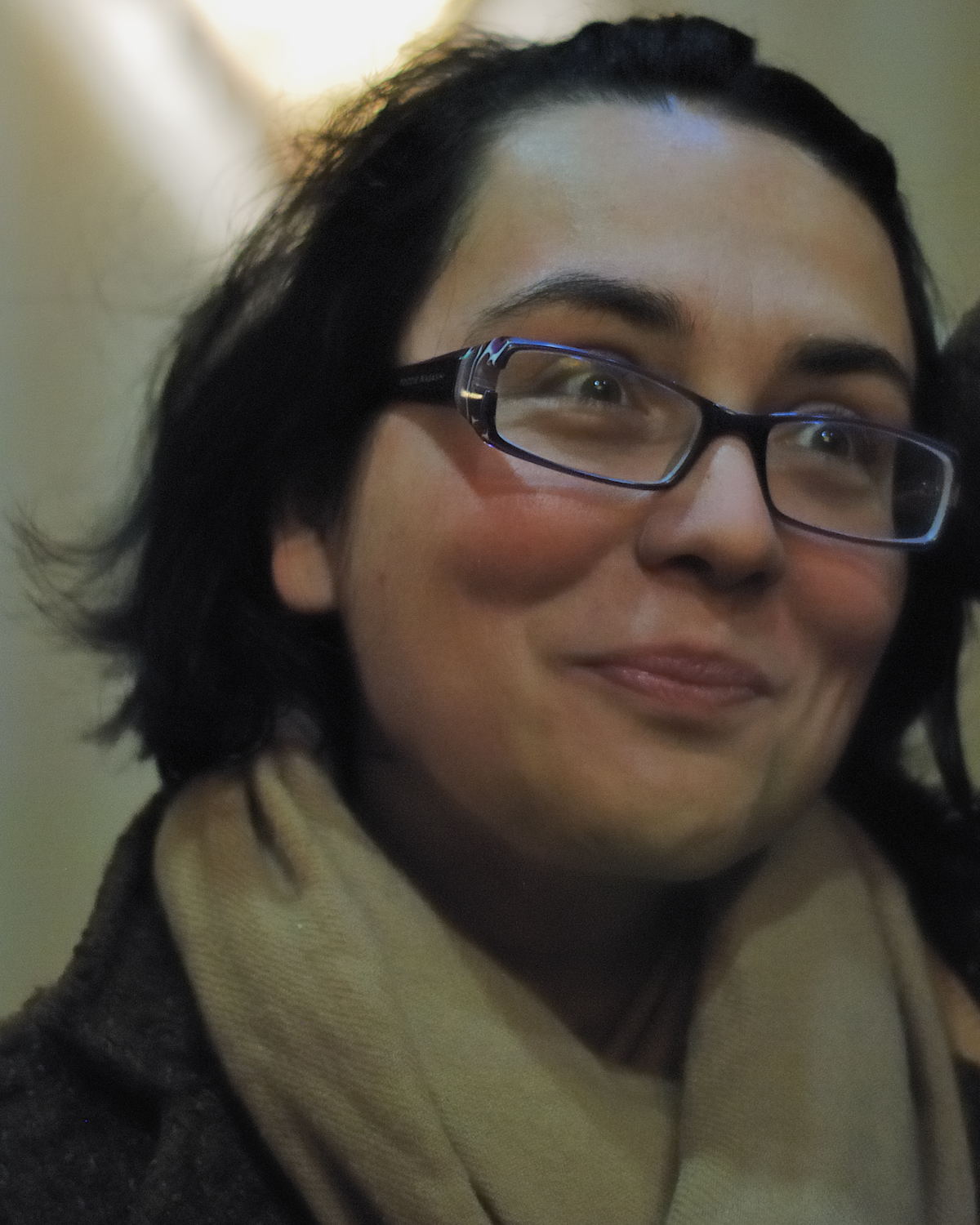 a woman wearing glasses while smiling in a room