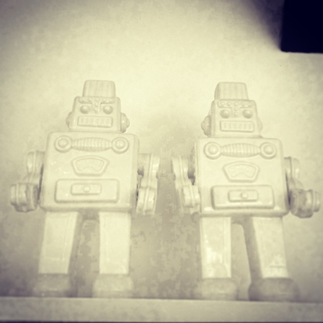 two toy robot statues sitting on a shelf