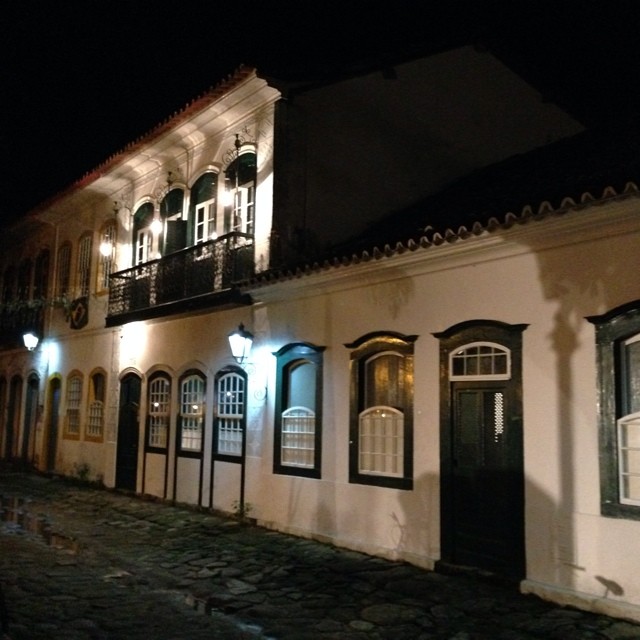 a cobblestone road next to a building at night
