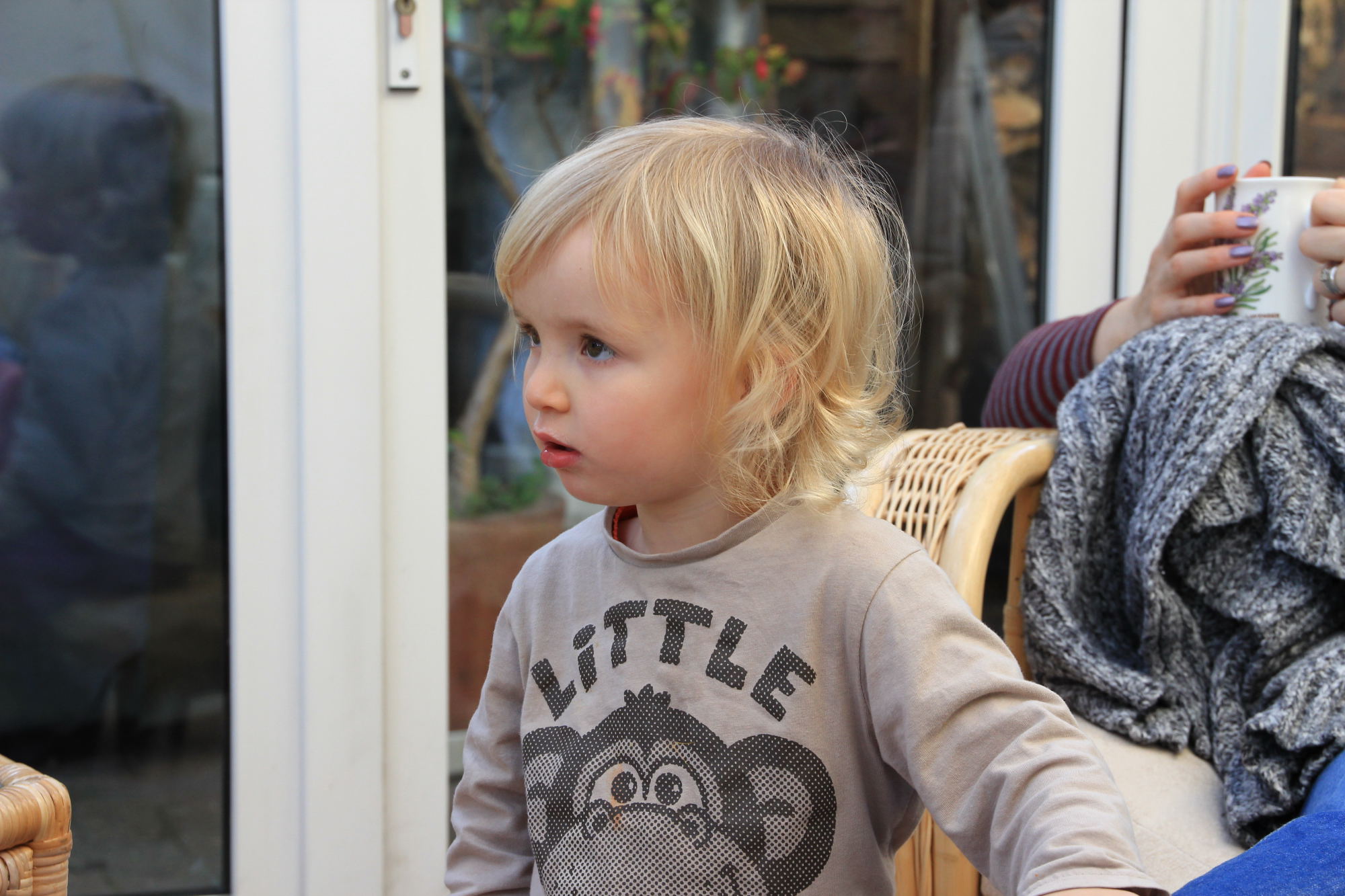 the little girl is sitting at the table outside with her hand on her hips