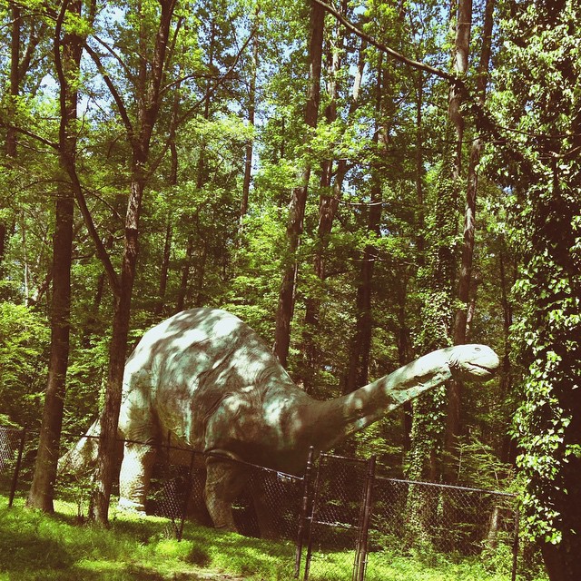 a large dinosaur statue is in the middle of the trees