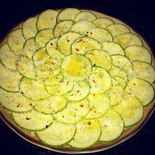 a pizza on a pan topped with zucchini slices