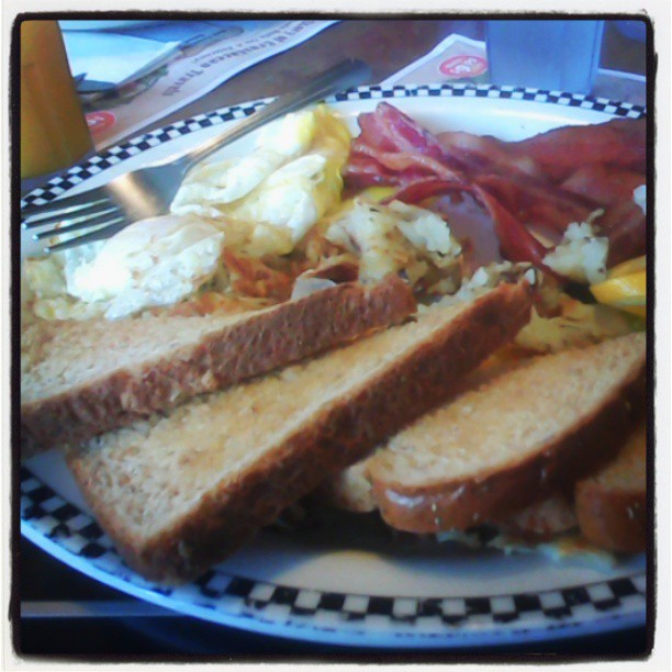 the large plate of food has bacon, eggs, potatoes, and toast