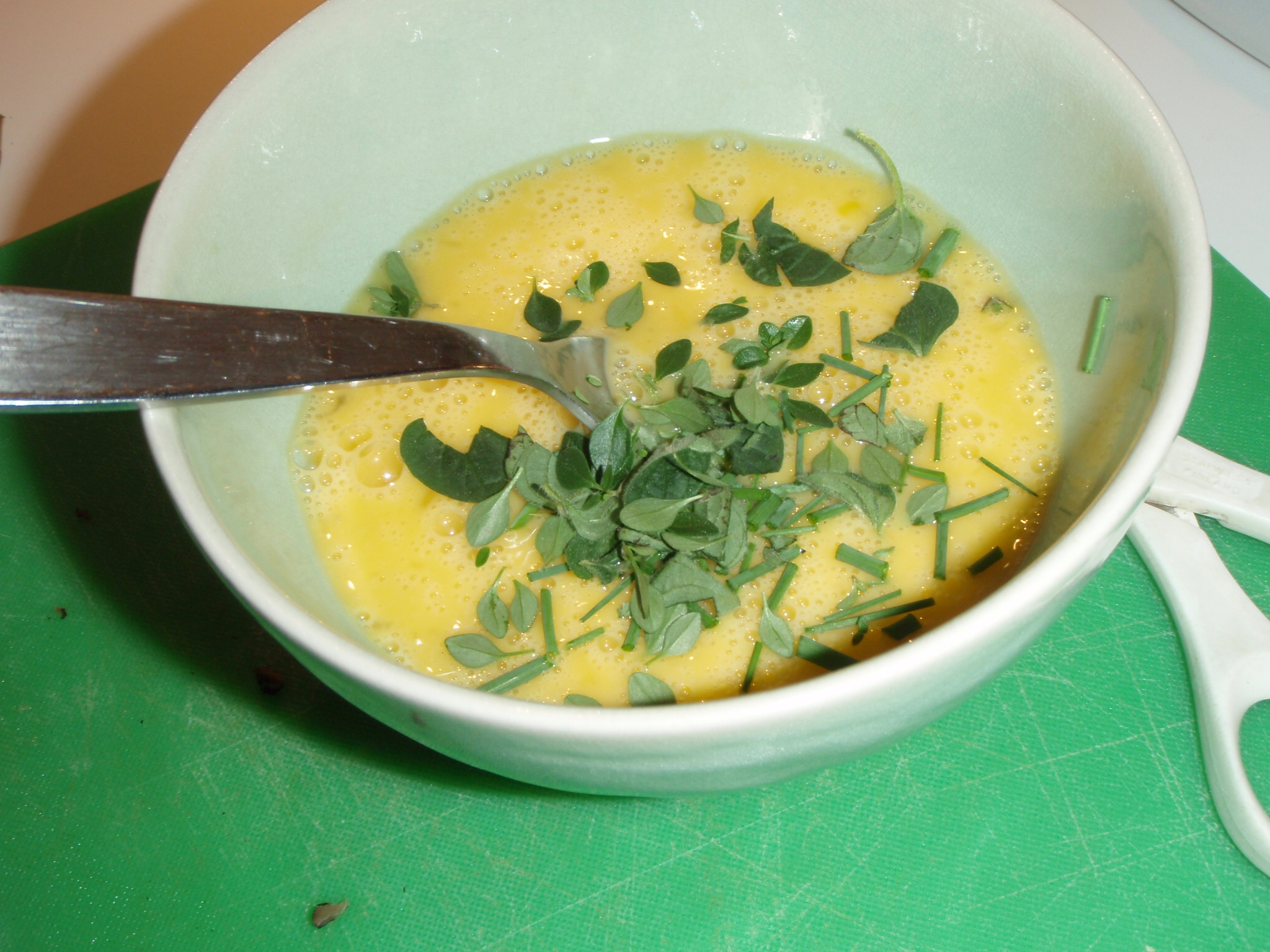 bowl filled with yellow sauce topped with fresh green herbs