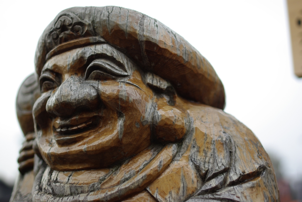 the wooden statue is carved to look like a laughing buddha