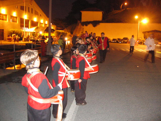 several children in costumes are marching down the street