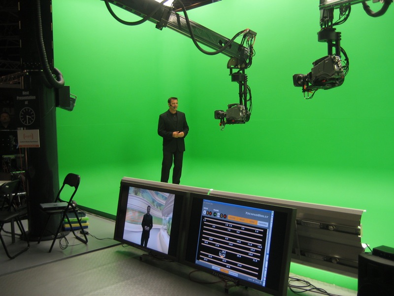 a man standing next to two monitors and green screen