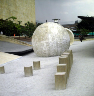 an outdoor area features cement blocks, wooden steps, and a concrete ball in the center