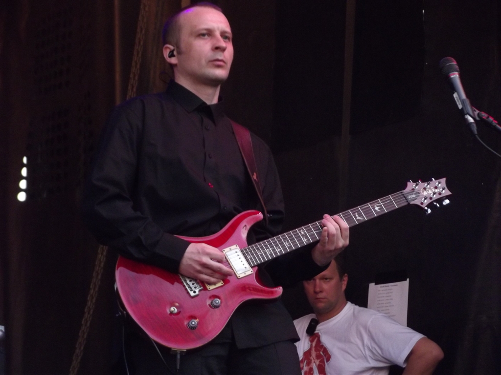 a man holding a pink guitar in front of another person
