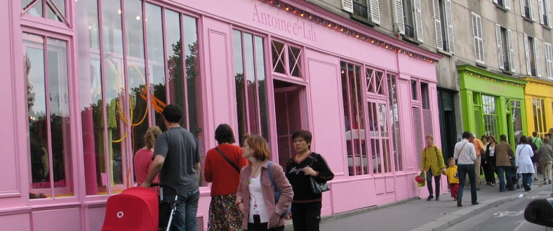 several people lined up outside of a pink building