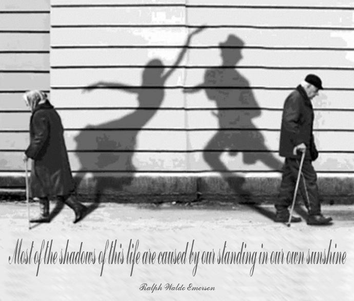 two men walking in front of a wall with a shadow and quote on it