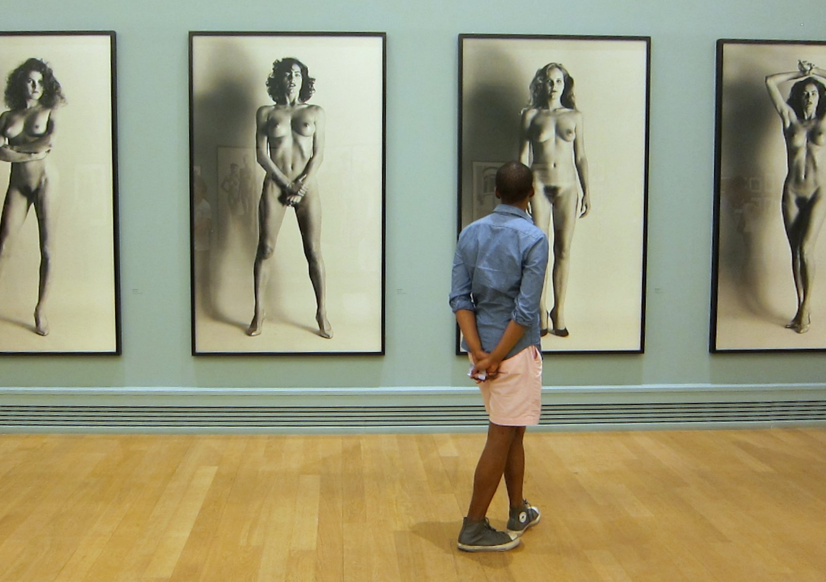 the woman stands on a wooden floor by three pictures of  women