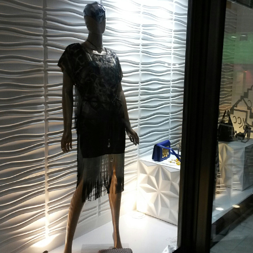 a mannequin dressed in fringed clothes stands behind a display