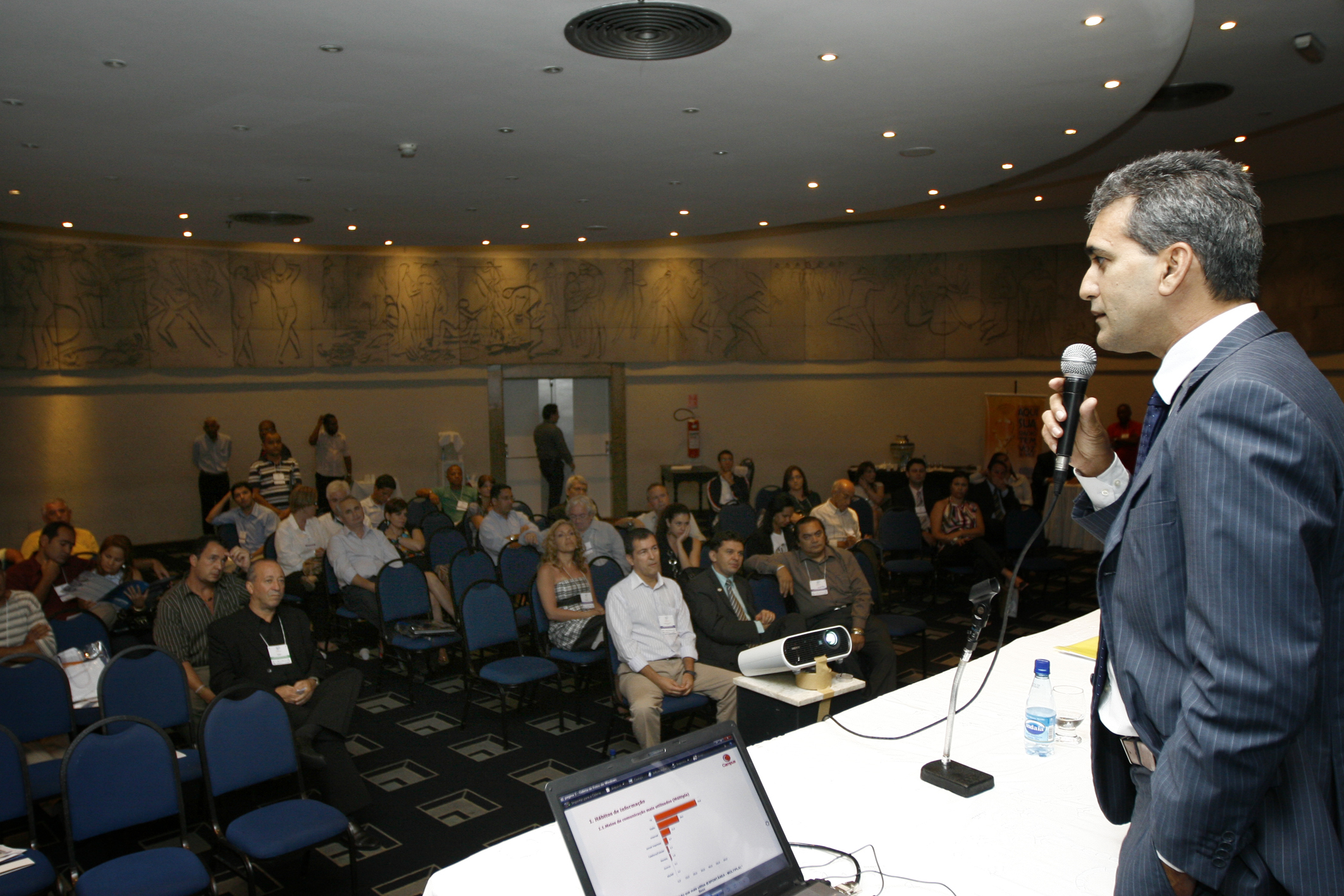 a speaker giving a lecture with his laptop in front of him