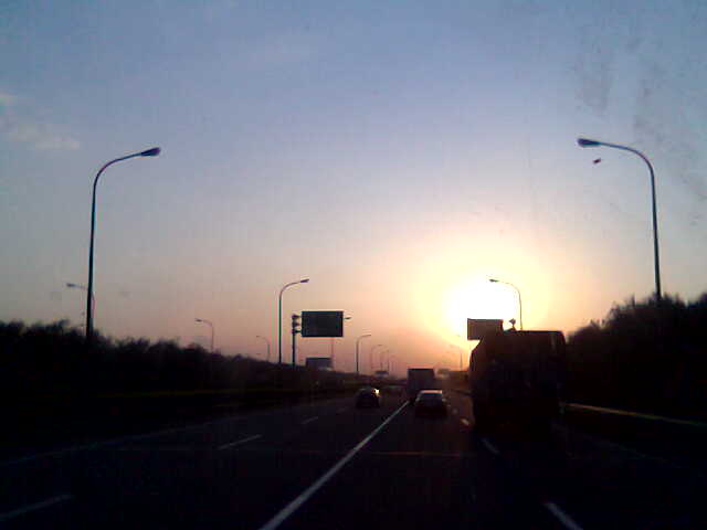 the sun is setting over the highway traffic