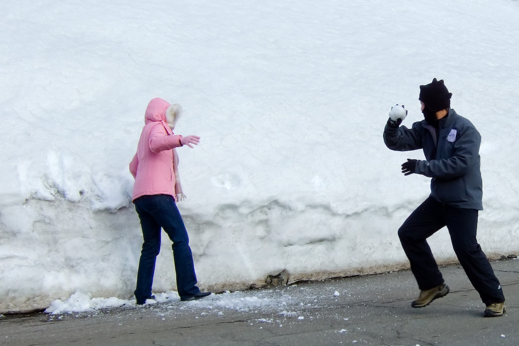 two people are standing in the snow by the curb