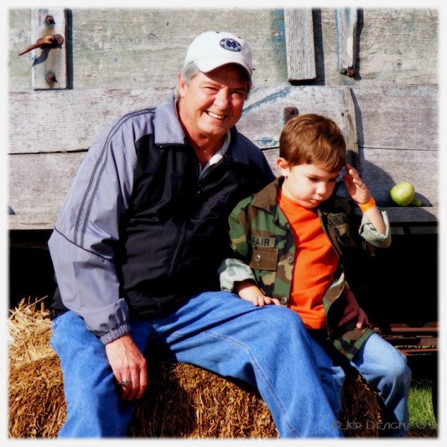 a man and child sit on a hay bale