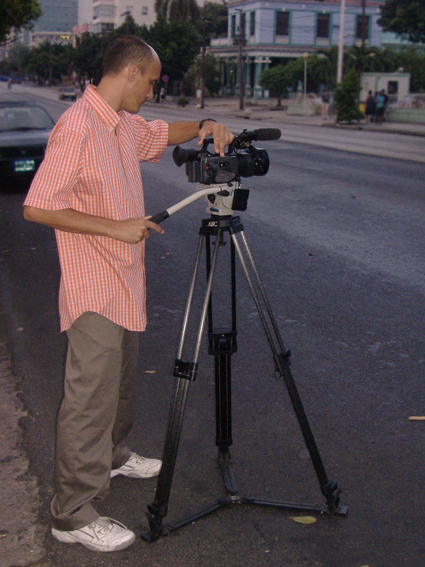 a man is standing on a street next to a tripod