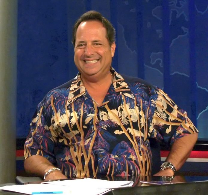 a man sitting at a desk with his arms crossed in a hawaiian shirt