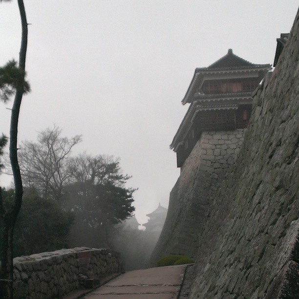 an alley lined with a stone wall and a small tower