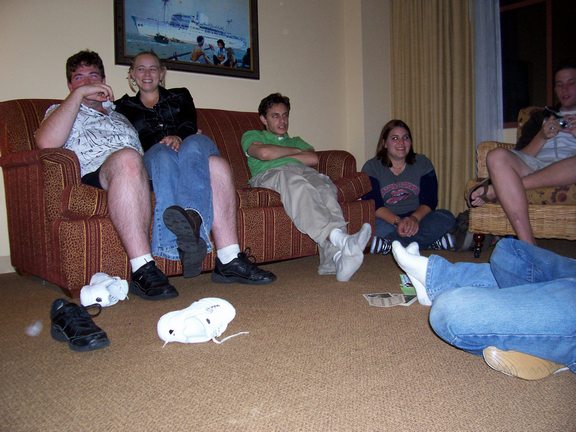 several people sitting on a couch with their legs crossed