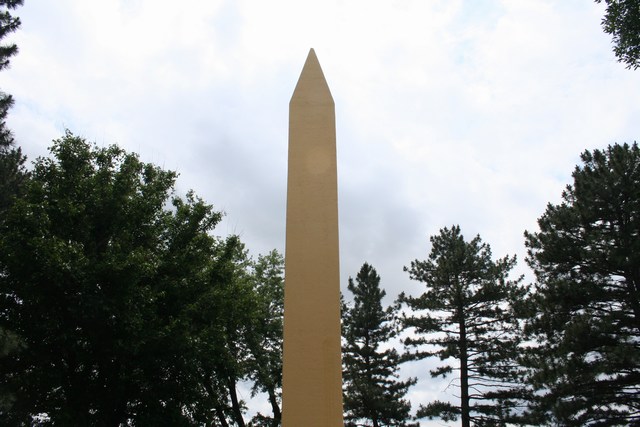 a tall white obelisk on a cloudy day