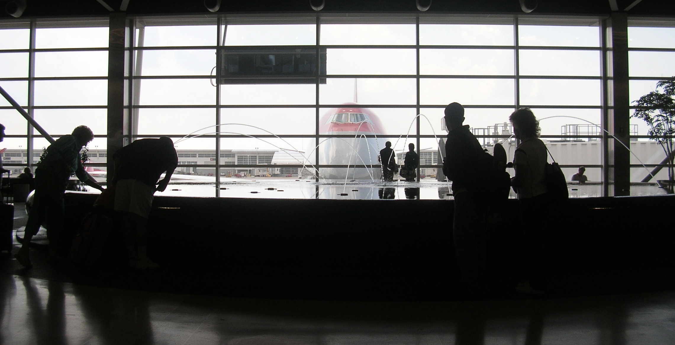 some people are standing near a big glass wall