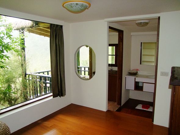 room with hard wood flooring and large window with view of trees