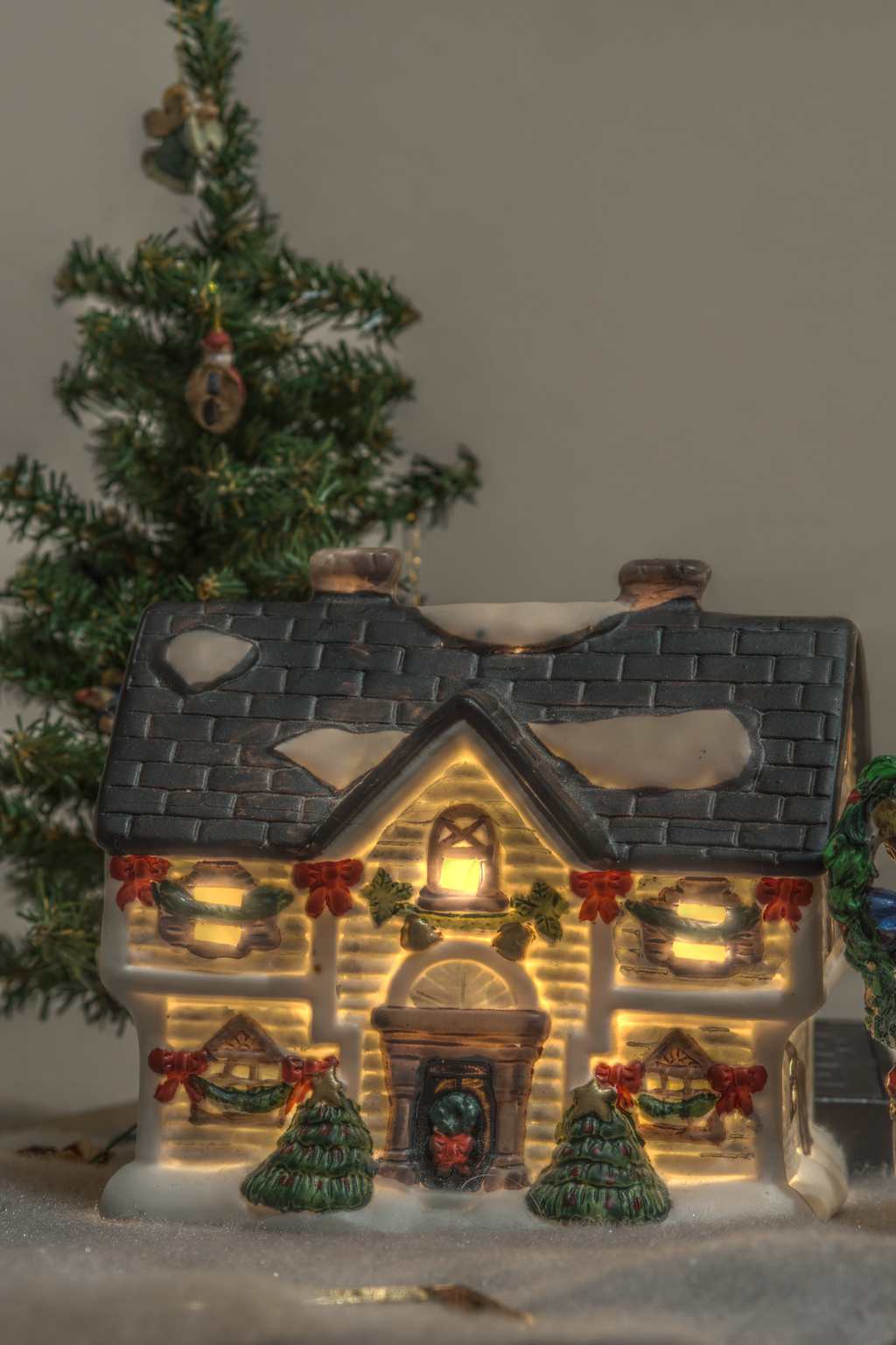 a lit up house next to a christmas tree